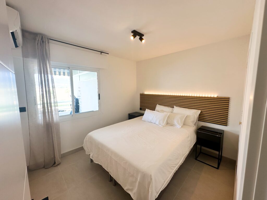 Slaapkamer met tweepersoonsbed en houten hoofdbord in Casa Delmolino