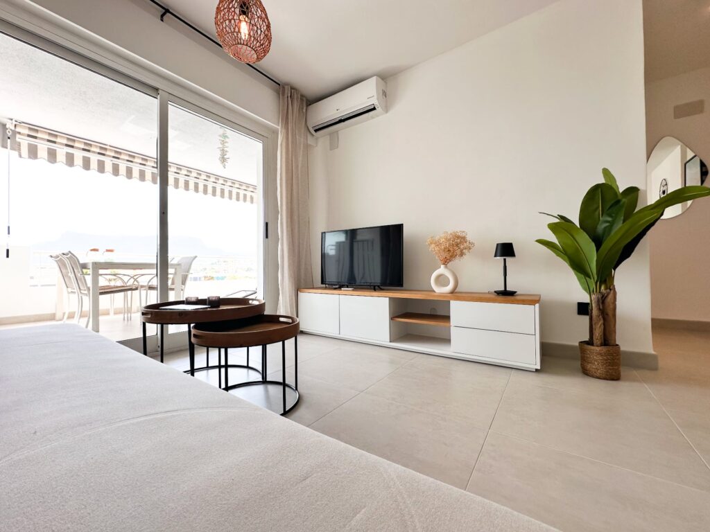 Woonkamer met tv-meubel en schuifpui naar het balkon
