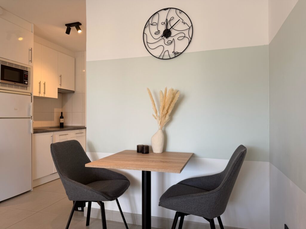 Eethoek met tafel voor twee en de open keuken van het appartement